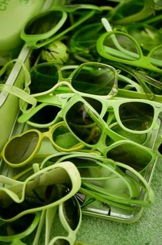 many pairs of green sunglasses sitting on top of each other next to a tube of toothpaste