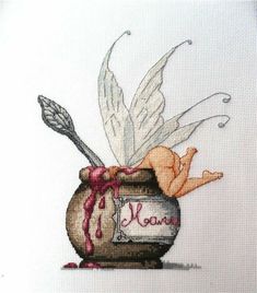 a cross stitch picture of a jar filled with honey