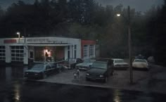 several cars parked in front of a building on a rainy night with the lights on