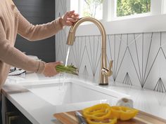 a woman washing vegetables in a kitchen sink with the faucet running from it