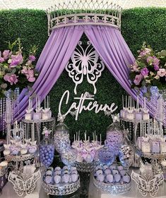 purple and white dessert table at a wedding reception with flowers on the wall behind it