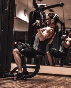 a man doing squats in front of a gym machine with headphones on his ears