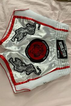 a close up of a white and red boxing bag on a bed with sheets in the background