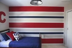 a red, white and blue striped wall in a child's room with a bed