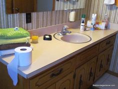 a bathroom sink with two rolls of toilet paper on the counter and one roll of tissue next to it