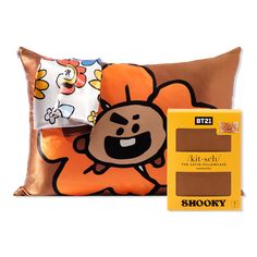 a pillow with an orange flower on it next to a box of chocolates and a sticker