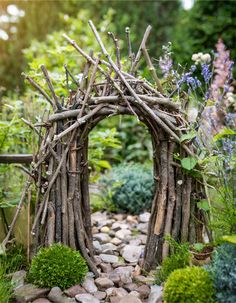 a garden with rocks, plants and branches in the shape of an arch made out of sticks