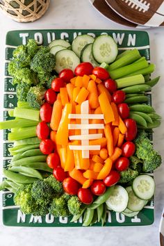 a football shaped veggie platter with carrots, broccoli and cucumbers