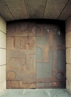 an open door in a stone wall with circles and squares on the outside, as if it were made out of concrete