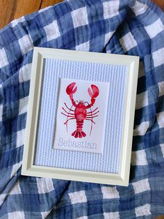 a blue and white gingham blanket with a red lobster in the frame on it