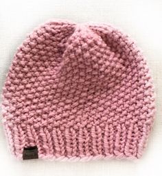 a pink knitted hat sitting on top of a white surface