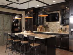 a kitchen with black cabinets and an island in the middle, surrounded by stools