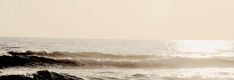 a man riding a surfboard on top of a wave in the ocean at sunset