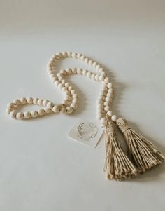 a white beaded necklace with tassels and a tag