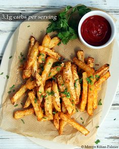 french fries on a plate with ketchup and parsley next to the side