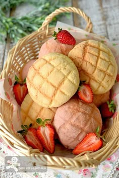 a basket filled with pastries and strawberries on top of a wooden table next to flowers