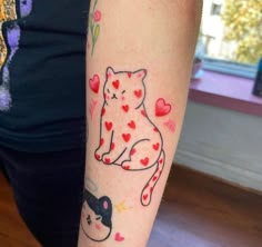 a woman's arm with a cat and hearts tattoo on the left side of her arm