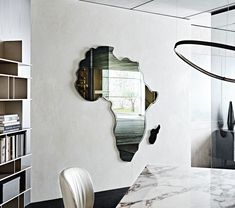 a mirror that is on the side of a wall next to a book shelf and table