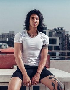 a man sitting on top of a cement bench next to a cityscape with buildings in the background