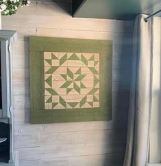 a green and white quilt hanging on the wall