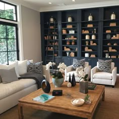 a living room filled with white furniture and lots of bookshelves on the wall