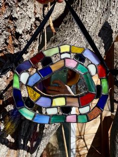 a stained glass sun catcher hanging on a tree branch with a hand reaching for it