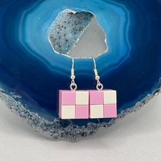 a pair of pink and white squares dangling from silver earwires on a blue background