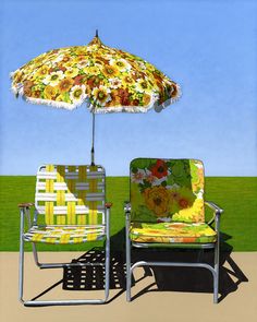 two lawn chairs and an umbrella on the beach in front of a grassy area with blue sky