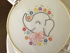 an elephant with flowers on it's head is embroidered onto a white hoop