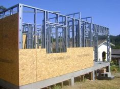 a house being built in the middle of a field with lots of wood and metal framing