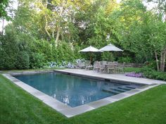 a pool surrounded by lush green grass and trees