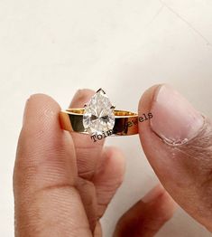 a person holding a ring with a diamond in it's middle and two fingers on the other side