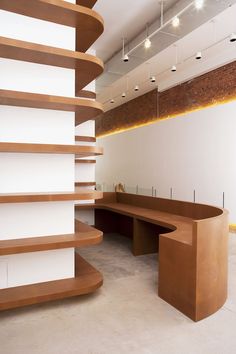 a curved wooden bench sitting in the middle of a room