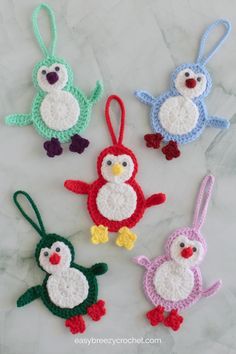 four crocheted penguin ornaments hanging on a marble surface with text overlay that says, free crochet penguin ornament pattern