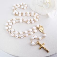 This Personalized Rosary, is ideal as a Baptism gift for a little girl or baby boy or as a gift for a special occasion. It is expertly handcrafted in a traditional style with a contemporary twist utilizing genuine Mother of pearl stone and gold-plated brass wire, which not only gives a touch of nature but also tenderness. The letter beads on the Rosary are also handmade from genuine mother of pearl, and the length is perfect to worn as a dainty Rosary necklace for women. *MATCHING ROSARY BRACELE White Spiritual Cross Jewelry And Charms, Customized White Jewelry For Personalized Gifts, Handmade White Jewelry For Personalized Gift, Handmade Rosary With Round Beads For Baptism, White Cross-shaped Jewelry For Personalized Gift, White Cross Jewelry For Personalized Gift, Spiritual 8mm Beads Rosary For Baptism, Handmade Adjustable Rosary For First Communion, White Jewelry For Confirmation On Mother's Day