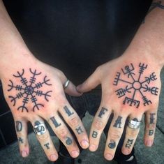 two people with tattoos on their hands are holding each other's hands and showing off their fingers