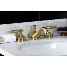 a bathroom sink with two gold faucets and marble counter top next to it