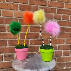 three potted plants with fake pom poms on them