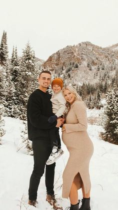 a man and woman holding a baby in the snow