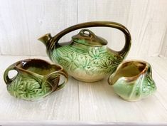 three pieces of green pottery sitting on a white surface