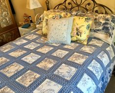 a bed with blue and white quilted bedspread, pillows and lamps on either side