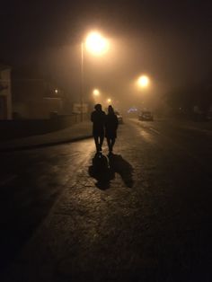 two people walking down the street at night