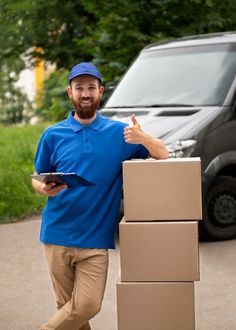 a man is standing next to boxes and giving the thumbs up