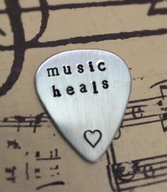 a guitar pick with the words music heals on it