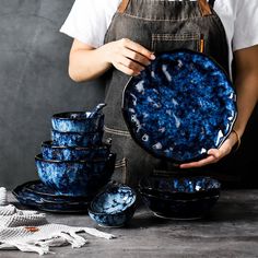 a person holding a plate with blue designs on it and several bowls in front of them