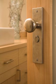 a door handle on the side of a wooden door in a bathroom with drawers and cabinets