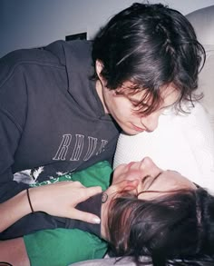 two people laying on top of each other with their faces close to one another and looking at the camera