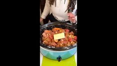 a woman standing in front of a pot filled with food