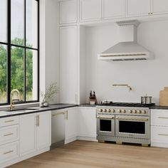 a kitchen with white cabinets and black counter tops, gold trim on the oven hood