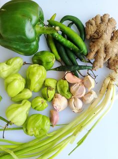 several different types of vegetables on a white surface with green beans, garlic and ginger